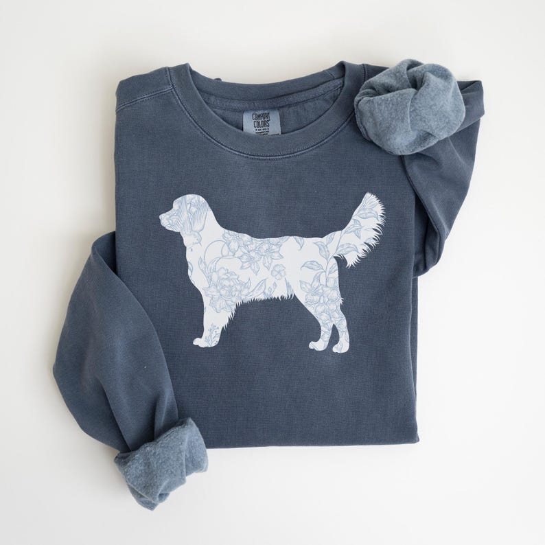 Op de afbeelding: Een marineblauw sweatshirt met een witte bloemenhondsilhouet. Het hondenontwerp is gevuld met een delicaat bloemenpatroon. De sweatshirt heeft een ronde hals en lange mouwen met manchetten. Het Comfort Colors-merkteken is zichtbaar.