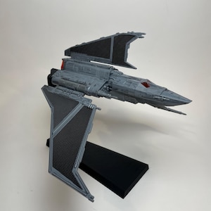May include: A gray and black Star Wars TIE Interceptor model with a black stand. The model has a detailed design and is a great addition to any Star Wars fan's collection.