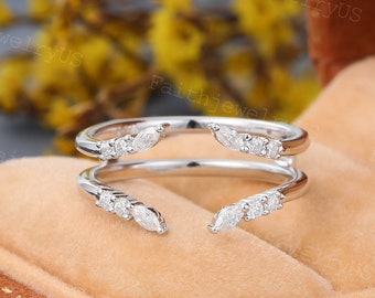 May include: A delicate silver ring with two bands, each adorned with marquise-shaped diamonds. The ring is designed to be worn as a double ring, with the two bands overlapping.