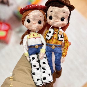 Puede incluir: Muñecos de ganchillo de Jessie y Woody de Toy Story. Jessie lleva un sombrero rojo, una camisa blanca y vaqueros azules. Woody tiene un sombrero marrón, una camisa amarilla y vaqueros azules. Ambos muñecos tienen rasgos faciales detallados.