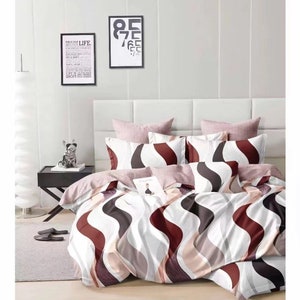 May include: A bed with a white headboard and a bedding set. The duvet cover and pillowcases have a wavy pattern in white, brown, and burgundy. Solid pink and patterned decorative pillows complete the look. Two framed art pieces hang on the wall.