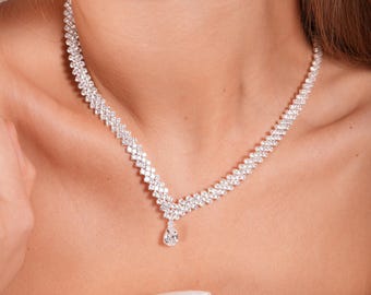 May include: A silver necklace with a teardrop-shaped pendant, both adorned with sparkling clear rhinestones.