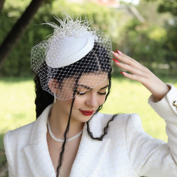 Vualet blanc fait à la main avec des plumes et des perles pour la mariée. Chapeau de mariage avec voile de visage en tulle. Coiffe de mariage élégante. Chapeau de mariage de style.