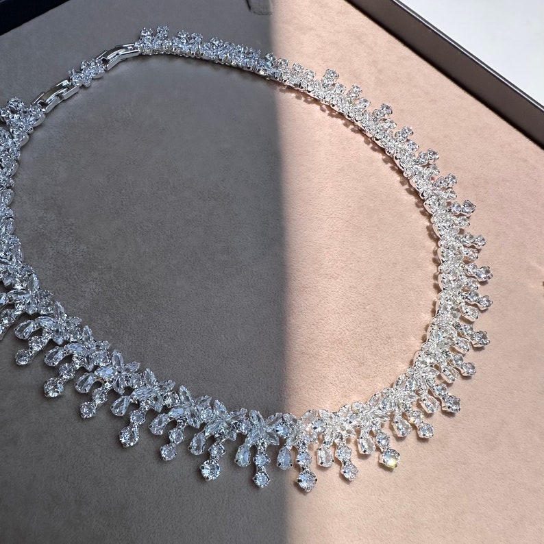 May include: A silver necklace with a teardrop design, featuring a cascade of sparkling clear stones.