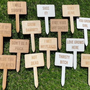 May include: A set of 14 wooden garden stakes with humorous and cheeky messages. The stakes are made of natural wood and have a rustic look. The messages include "Succ it up you got this", "Grow dammit!" and "I wet my plants".