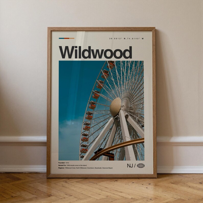 May include: A framed poster featuring a Ferris wheel against a blue sky. The word "Wildwood" is printed in large black letters at the top. The poster includes the text "NJ" and a globe icon.