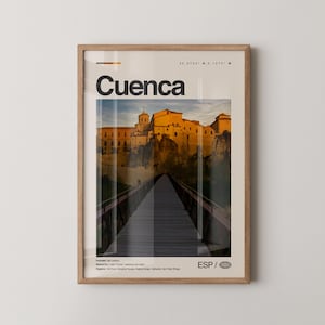 May include: A framed print featuring the word "Cuenca" in large black letters. The image shows a bridge leading to a city with golden-hued buildings. The print includes coordinates and the letters "ESP" with a globe icon, suggesting a Spanish location.