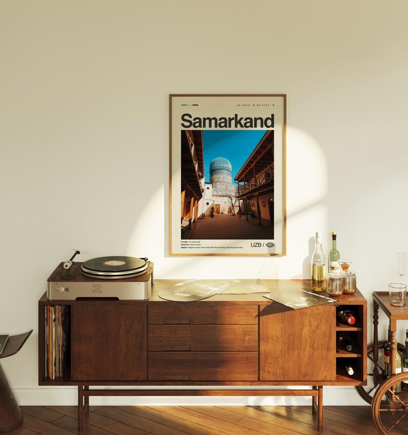 May include: A framed poster with the word "Samarkand" in large text, depicting a street scene with a blue-domed building. The poster is displayed above a wooden cabinet with a record player and bottles.