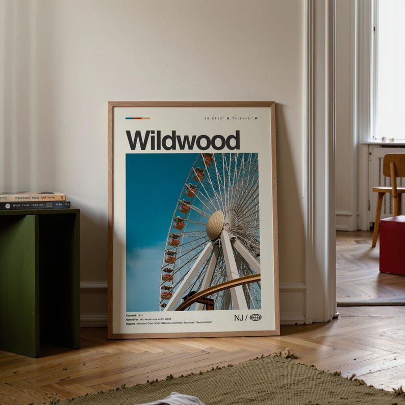 May include: A framed poster featuring the word "Wildwood" in bold black letters. The poster displays a photograph of a Ferris wheel against a bright blue sky. The poster includes the coordinates 38.9515&deg; N 74.6145&deg; W.