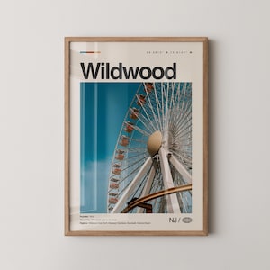 May include: A framed print featuring a Ferris wheel with red gondolas against a blue sky. The word "Wildwood" is printed in bold black letters at the top, with additional text and coordinates. The print is in a light brown wooden frame.