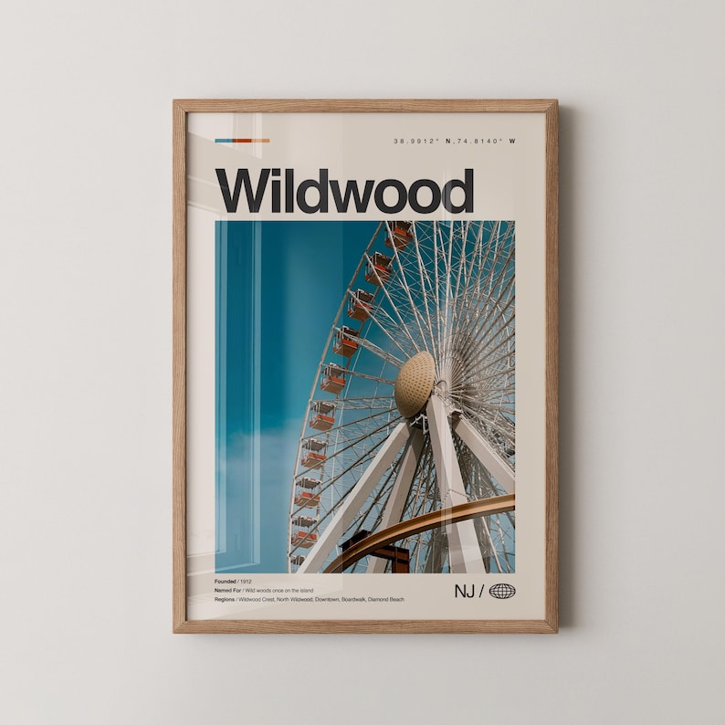 May include: A framed print featuring a Ferris wheel with red gondolas against a blue sky. The word "Wildwood" is printed in bold black letters at the top, with additional text and coordinates. The print is in a light brown wooden frame.