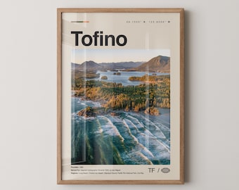 May include: A framed print displaying a scenic aerial view of Tofino, with the town's name in bold black letters at the top. The image shows a coastline with waves, trees, and mountains, with the text "TF /" at the bottom.