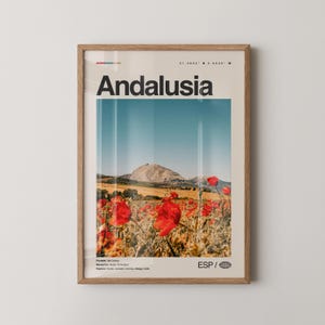 Può includere: Un poster incorniciato con la parola "Andalusia" in nero. L'immagine mostra un campo di papaveri rossi, una montagna e un cielo blu. Il poster include testo e coordinate. La cornice è in legno.