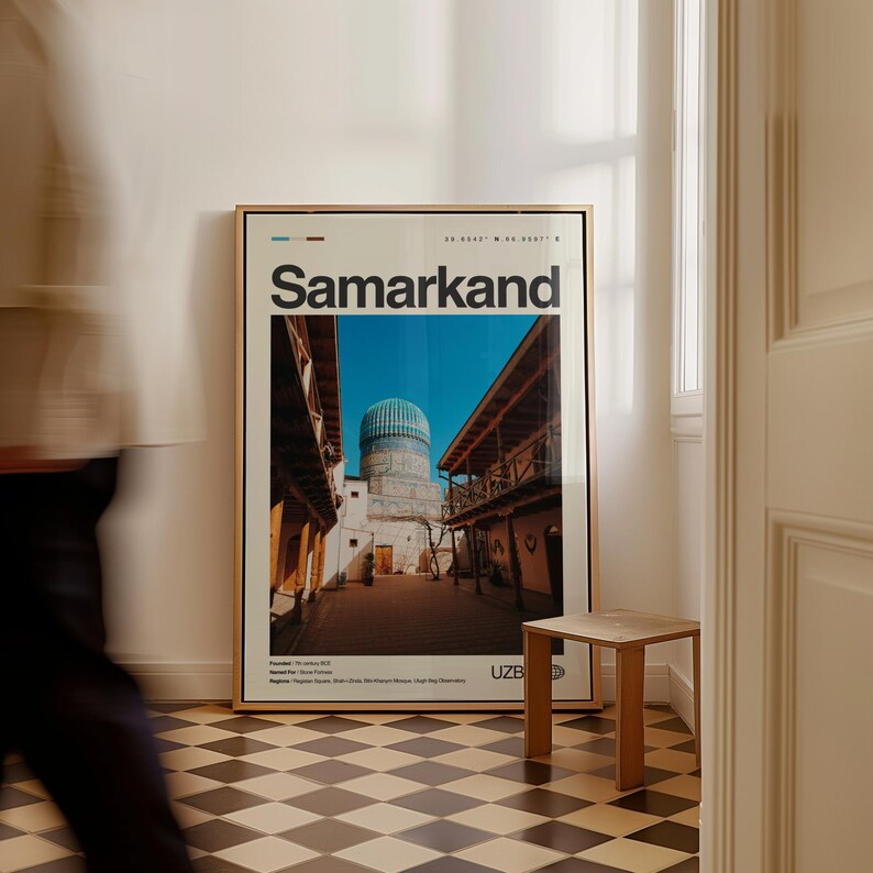 May include: A framed poster with the word "Samarkand" in large white letters. The image within the frame depicts a building with a blue dome and a courtyard. A small wooden side table sits in front of the poster.