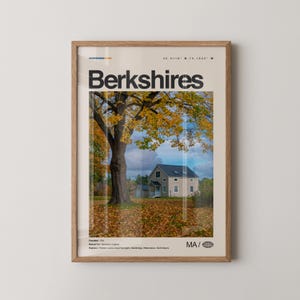May include: A framed poster featuring a scenic autumn landscape of the Berkshires. The image includes a large tree with yellow leaves, a house, and the text "Berkshires" in bold black letters. The poster is in a wooden frame.