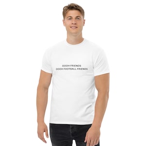 May include: White t-shirt with black text that reads "OOOH FRIENDS OOOH FOOTBALL FRIENDS"