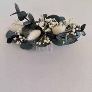 May include: A dark green eucalyptus and white baby's breath floral hair comb with a silver comb.