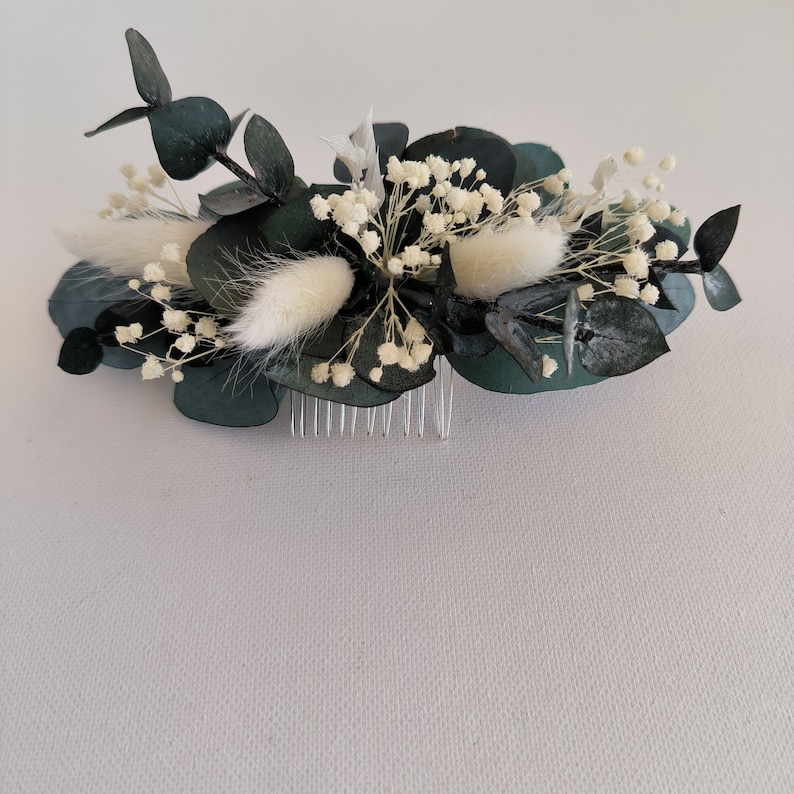 May include: A dark green eucalyptus and white baby's breath floral hair comb with a silver comb.
