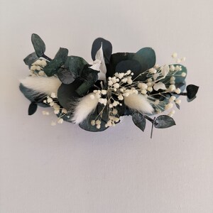 May include: A green eucalyptus and white baby's breath floral arrangement. The arrangement is made with dried flowers and is perfect for adding a touch of natural beauty to any space.