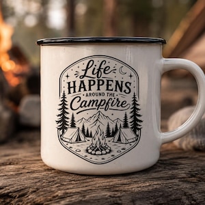 May include: A white enamel mug with a black rim and a black graphic print featuring the text Life Happens Around the Campfire, accompanied by illustrations of a campfire, two tents, pine trees, mountains, a crescent moon, and small stars.