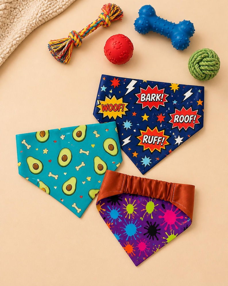 May include: A collection of dog bandanas with playful patterns and phrases, alongside dog toys. The bandanas feature avocado, bone, and comic book-style designs with phrases like "Woof!" and "Bark!" in vibrant colors.