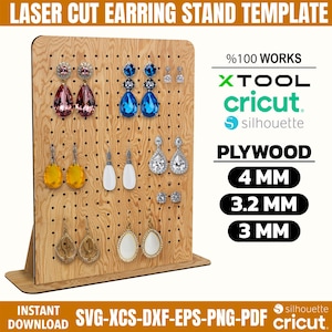 May include: A wooden laser-cut earring stand template with various earrings displayed. The stand is made of plywood and has multiple holes for hanging earrings. Text on the stand includes "LASER CUT EARRING STAND TEMPLATE" and "PLYWOOD 4 MM, 3.2 MM, 3 MM".