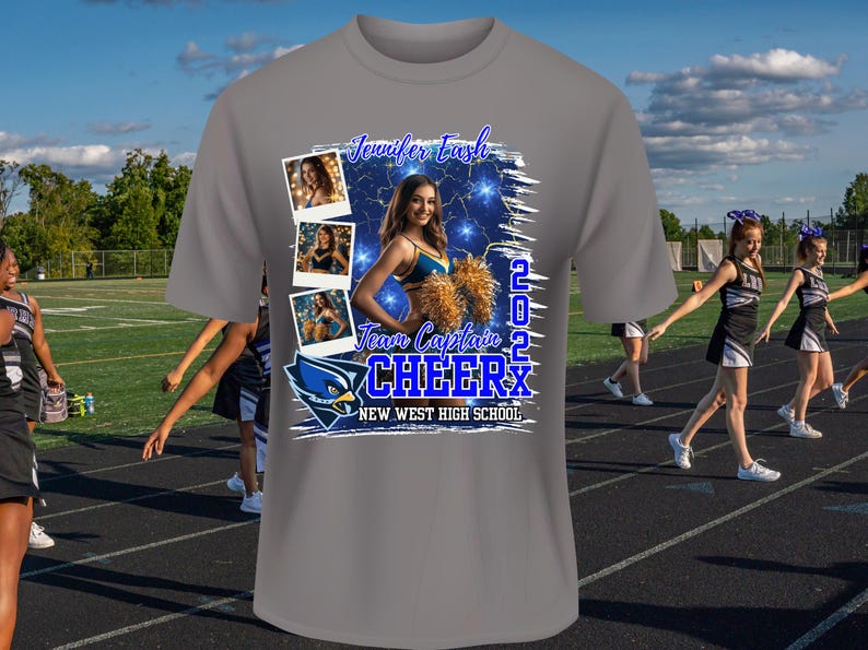 May include: Gray t-shirt with a blue and white graphic design featuring a cheerleader with pom-poms and the text "Jennifer Eash Team Captain 2022 Cheer New West High School".