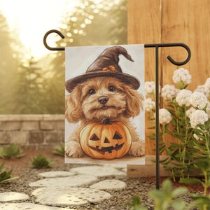 May include: A brown and white dog wearing a witch's hat holds a jack-o'-lantern in its paws. The dog is sitting on a white background with a black border. The image is a Halloween-themed garden flag.