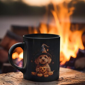 May include: A black ceramic mug with a Halloween-themed design featuring a brown and white dog wearing a witch's hat and holding a jack-o'-lantern. The mug is sitting on a wooden surface in front of a blurred background of a campfire.