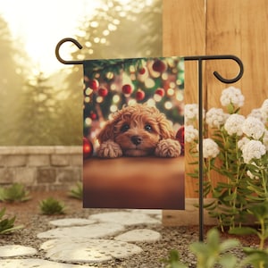 May include: A brown and white puppy with its head resting on a table, looking at the camera. The puppy is in front of a Christmas tree with red baubles and fairy lights.