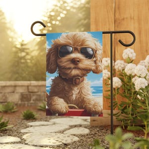 May include: A garden flag featuring a cartoon illustration of a brown and white dog wearing sunglasses. The dog is looking at the camera and has a happy expression. The background is a blue sky with white clouds and a beach scene.