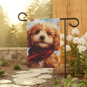 May include: A brown and white puppy with a red bandana around its neck is featured on a garden flag. The flag is hanging from a black metal stand.