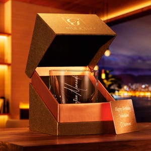 May include: A brown box with a gold interior, containing a clear glass with an inscription that reads "Christian Howard". The box is open and a small gold card with the text "Happy Birthday Sebastian!" is visible.