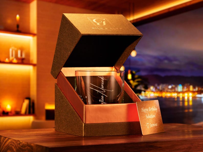 May include: A brown box with a gold interior, containing a clear glass with an inscription that reads "Christian Howard". The box is open and a small gold card with the text "Happy Birthday Sebastian!" is visible.