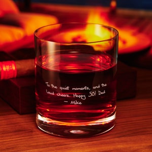 May include: A clear glass tumbler with a handwritten message that reads "To the quiet moments, and the loud cheers. Happy 50! Dad - Mike". The glass is filled with a dark red liquid.