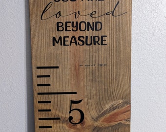 May include: A wooden growth chart with black markings and the text "You are loved beyond measure". The chart has a number "5" marked on it.