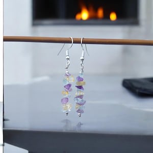 Puede incluir: Un par de pendientes de plata con una mezcla de piedras preciosas azules, moradas y amarillas.