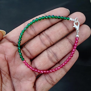 Peut inclure: Un bracelet en perles de pierres précieuses vertes et rouges avec un fermoir argenté. Le bracelet est composé de petites perles rondes.