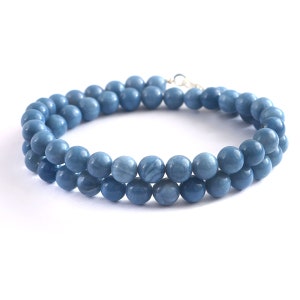 Pode incluir: Um colar de pedras preciosas azuis feito de contas redondas. O colar é de cor azul claro e tem um fecho prateado.