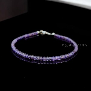 Puede incluir: Un delicado brazalete de amatista púrpura con cierre de plata. El brazalete está hecho de pequeñas cuentas redondas y mide aproximadamente 18 cm de largo.