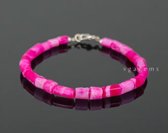 May include: A vibrant pink bracelet with rectangular beads and a silver clasp. The beads have a marbled effect with shades of pink and white. The bracelet is displayed on a reflective surface. The text "vgagems" is visible.