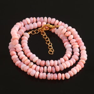 May include: A pink opal gemstone necklace with a gold clasp. The necklace is made of small, faceted beads and is layered in a double strand.