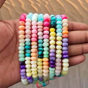 May include: A collection of colorful round beads, each with a unique marbled pattern. The beads are strung together in a long strand, creating a vibrant and eye-catching display.