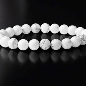May include: White gemstone bracelet with round beads.