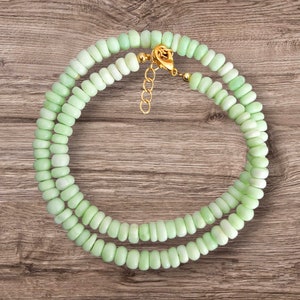 Könnte beinhalten: Eine zweireihige Halskette aus hellgrünen Perlen mit einem goldenen Verschluss.