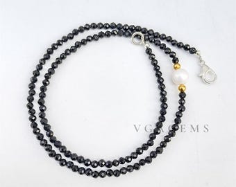 以下が含まれることがあります： 黒いビーズネックレス、パールとゴールドのアクセント付き。 ネックレスは、小さなファセットブラックビーズで構成され、白いパールとゴールドカラーのビーズが特徴です。 シルバーの留め金がネックレスを固定します。