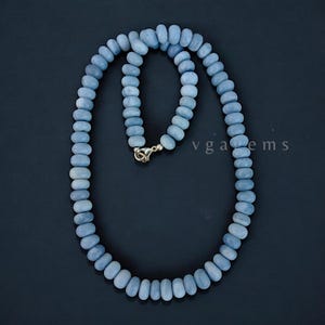 Op de afbeelding: Een ketting gemaakt van lichtblauwe opaal kralen. De ketting is ongeveer 45 cm lang en heeft een zilveren sluiting.