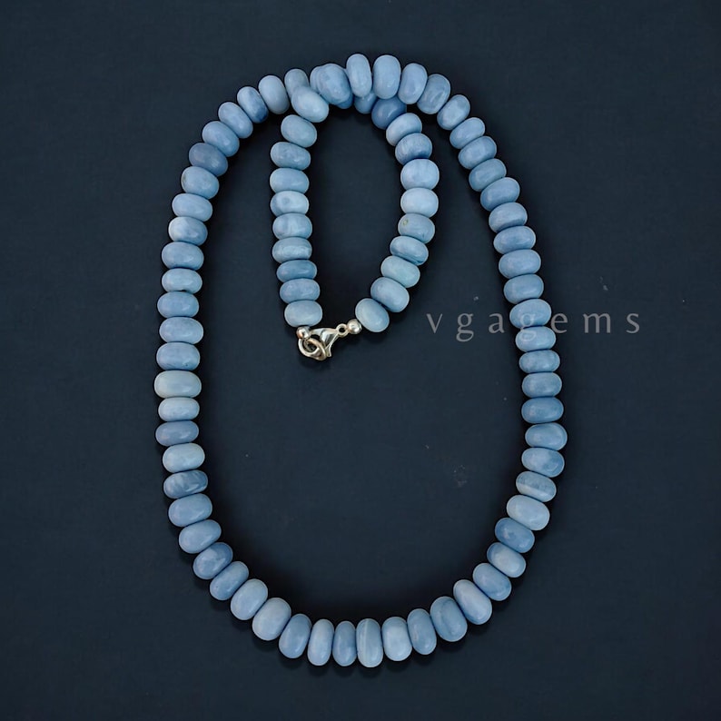 Op de afbeelding: Een ketting gemaakt van lichtblauwe opaal kralen. De ketting is ongeveer 45 cm lang en heeft een zilveren sluiting.