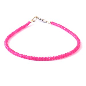 Puede incluir: Un delicado brazalete de piedras preciosas rosas con un cierre plateado. El brazalete está hecho de pequeñas cuentas facetadas.