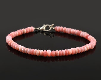 May include: A pink opal gemstone bracelet with a silver clasp. The bracelet is made of small, faceted beads.